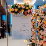 Wedding welcome sign with floral arrangement on a gold stand for A and B's celebration