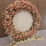 Circular wedding flower backdrop with pink and ivory roses and white draping