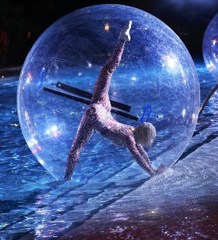 Female performer doing a split inside a transparent bubble on water during a live show